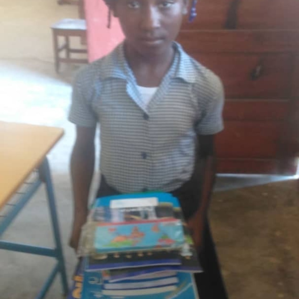 A boy holding a stack of books in his hands.