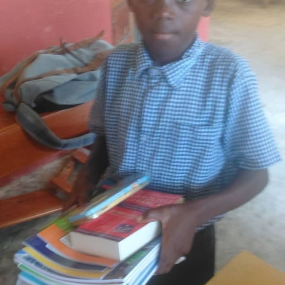 A boy holding books in his hands.