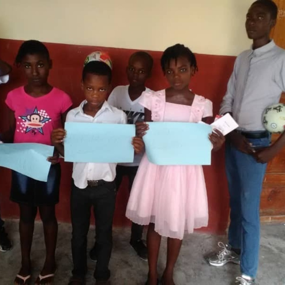 A group of children holding up papers in front of a wall.