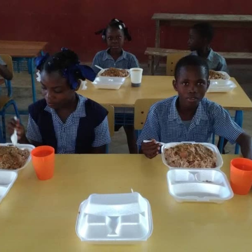 A group of children sitting at the table eating food.