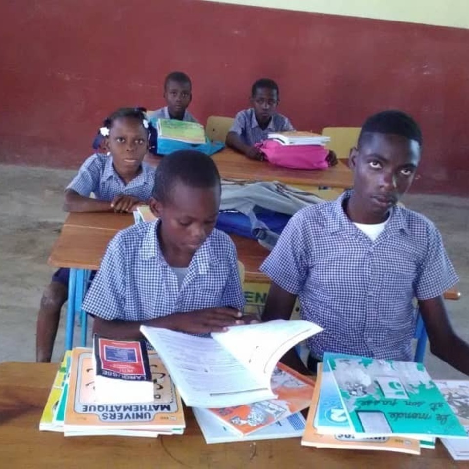 A group of children sitting at desks with books.