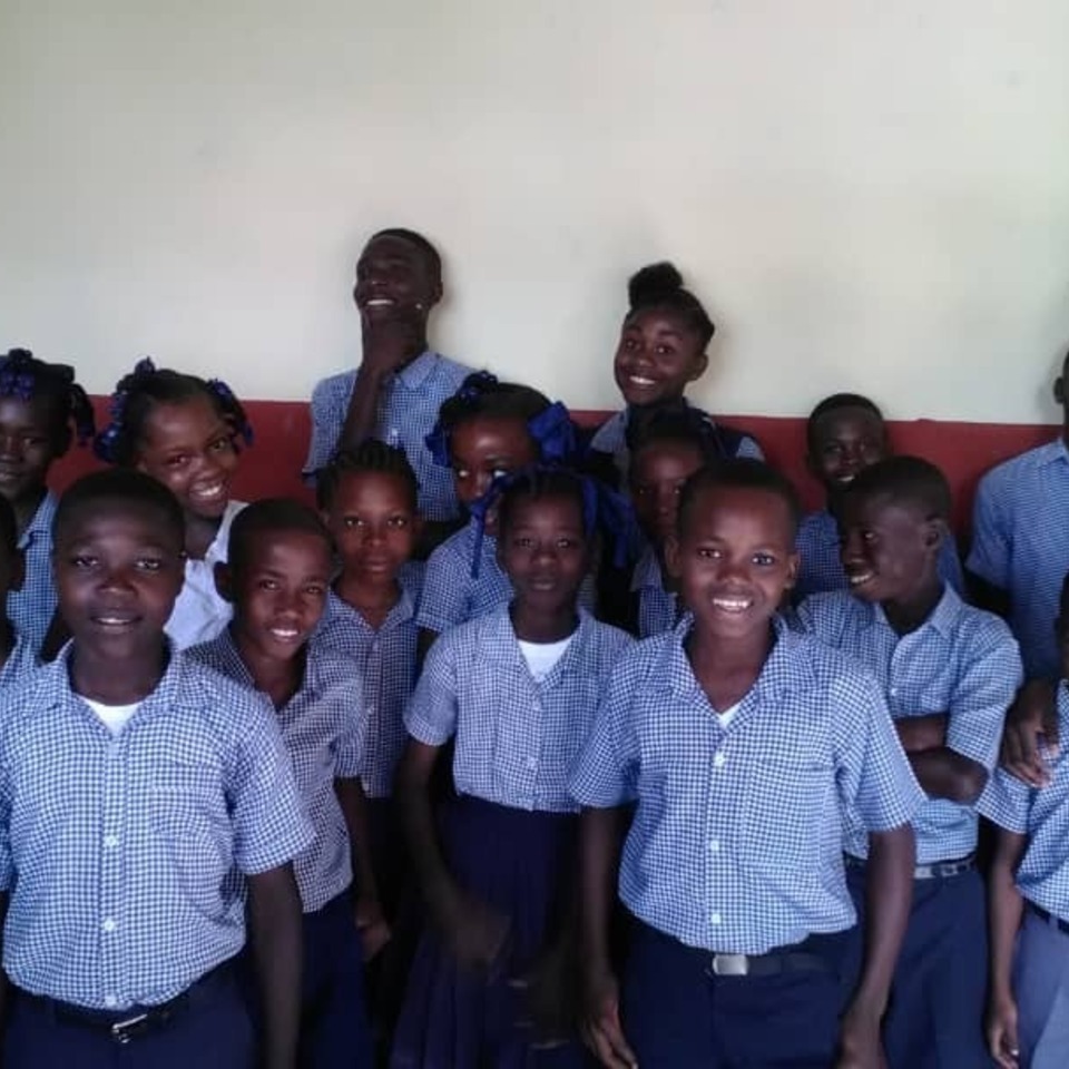 A group of young people standing together in front of a wall.