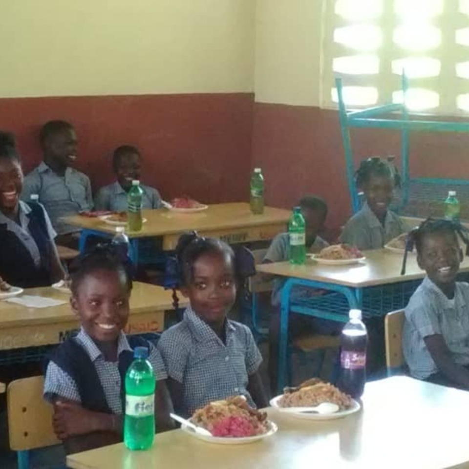 A group of children sitting at tables eating food.