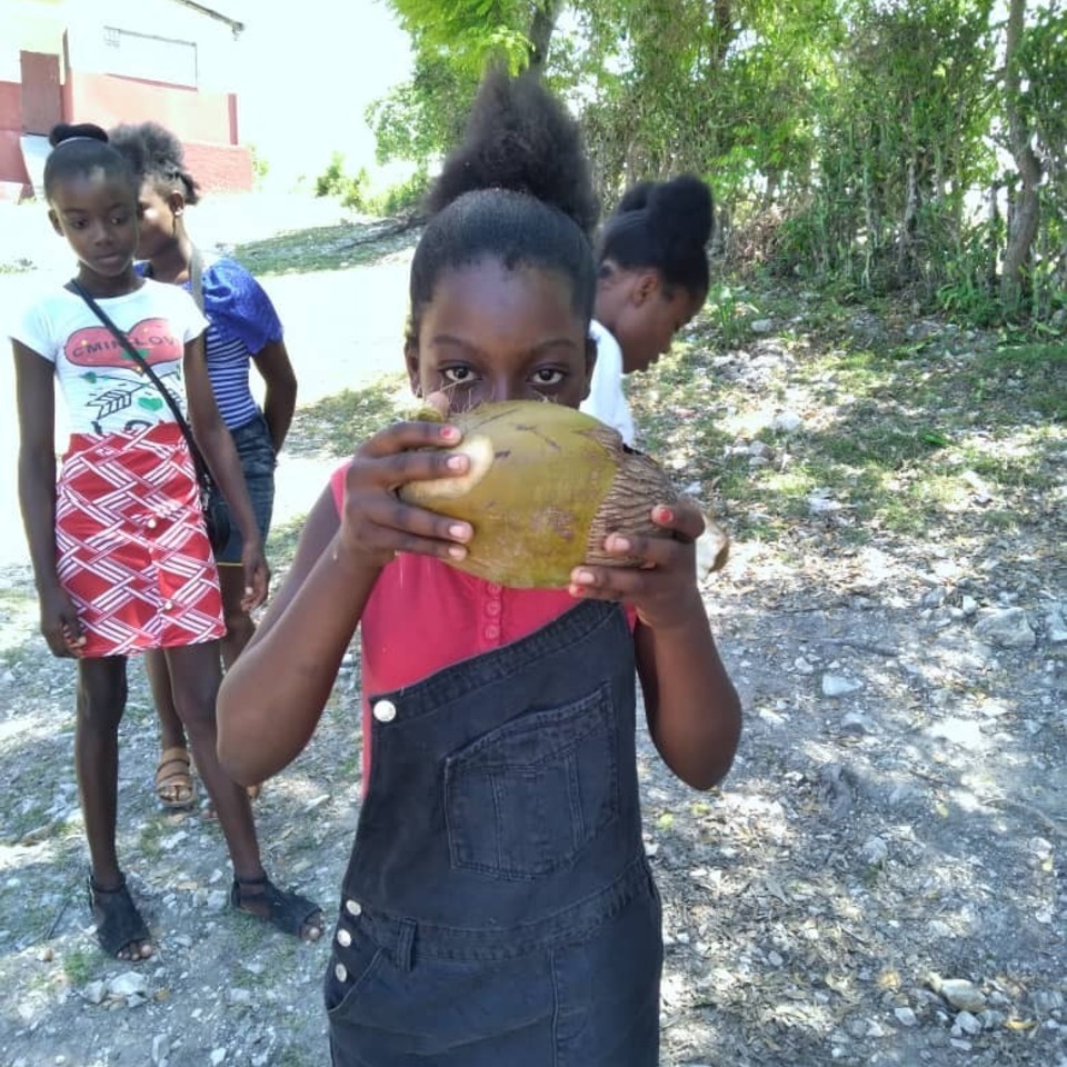 A girl holding up an orange to her face.