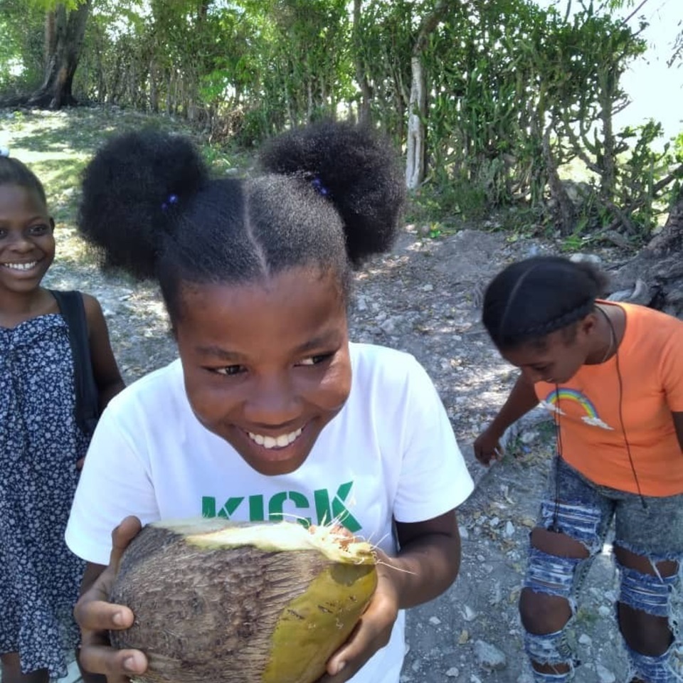 A group of children holding coconuts in their hands.