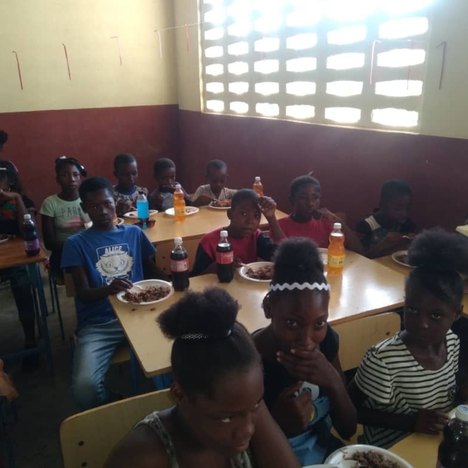 A group of children sitting at tables eating food.