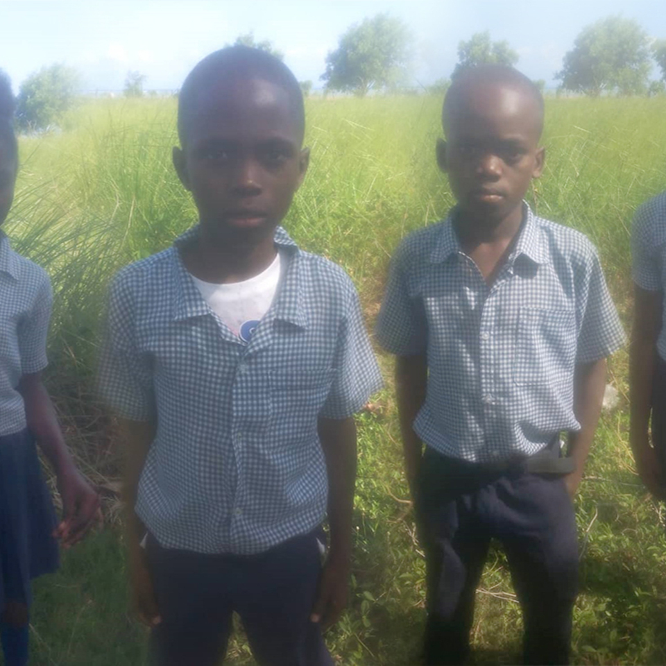 A group of young boys standing in the grass.