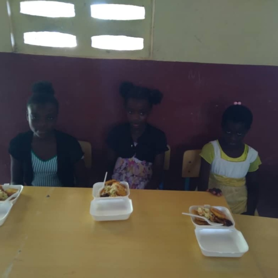 Three girls sitting at a table with food.