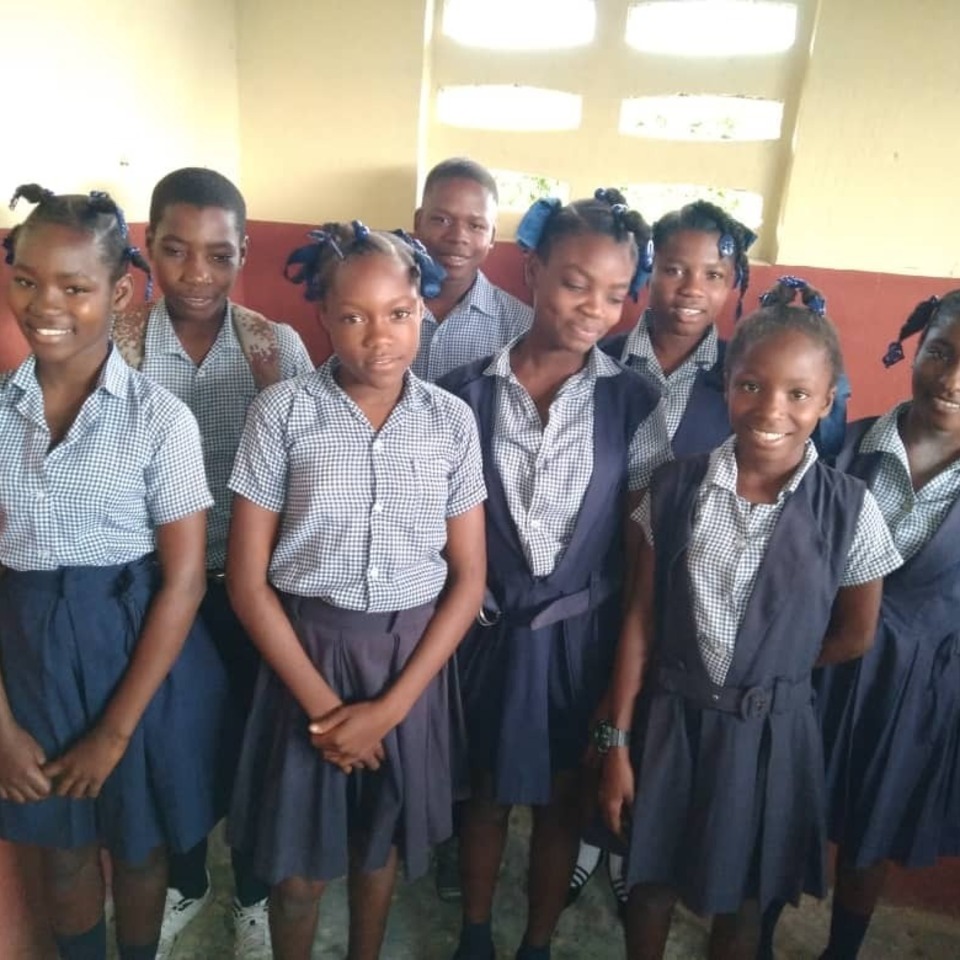 A group of children in school uniforms posing for the camera.