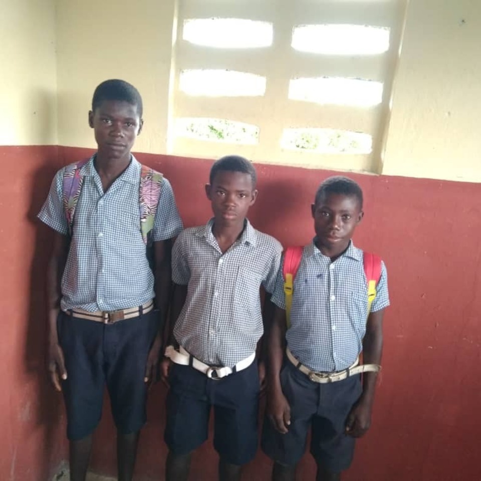 Three boys in uniforms standing next to each other.