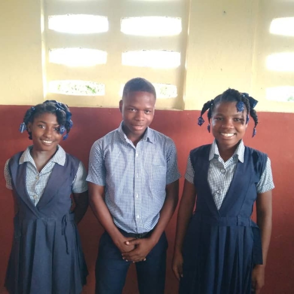 Three children standing in front of a wall.