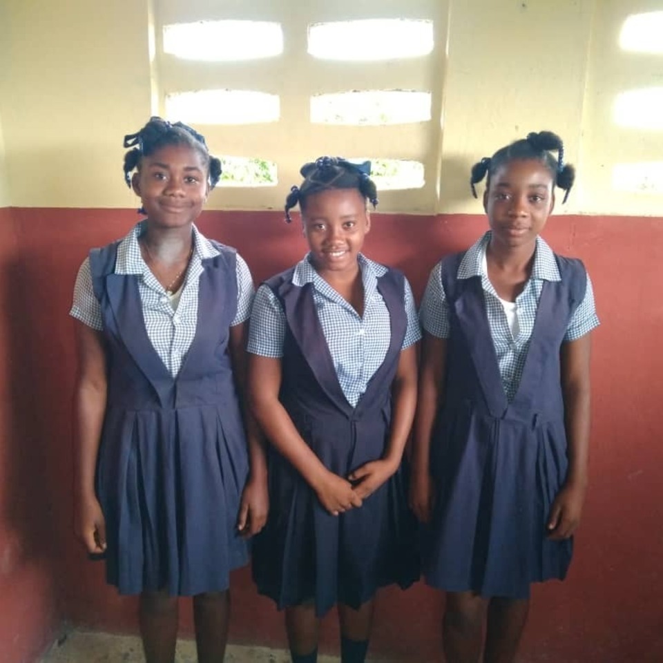 Three girls in school uniforms posing for a picture.