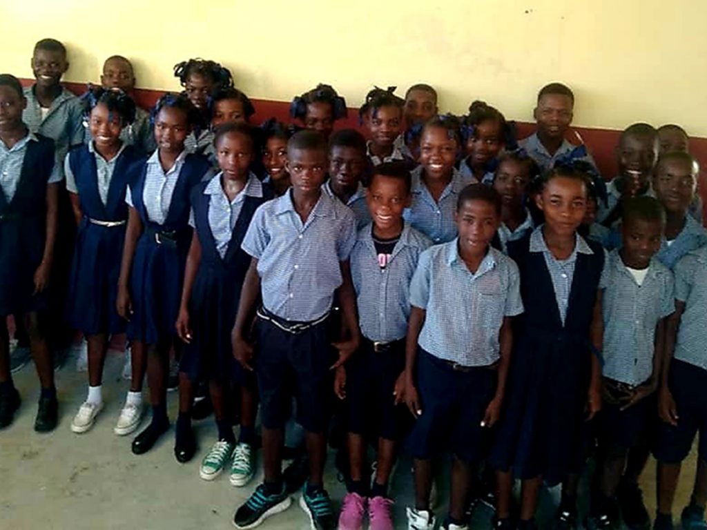 A group of children standing in front of a wall.