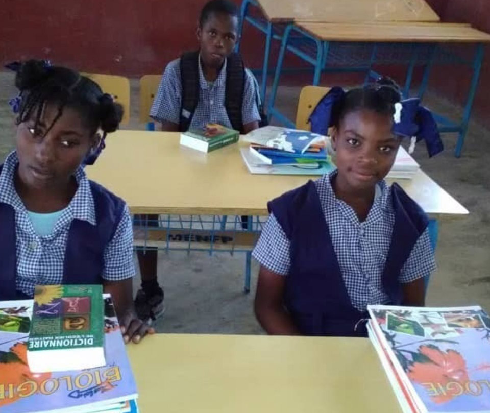 A group of children sitting at tables with books.