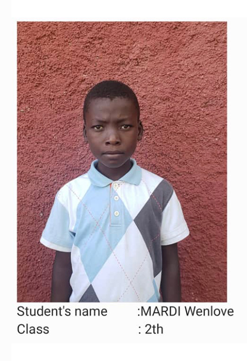 A young boy standing in front of a wall.