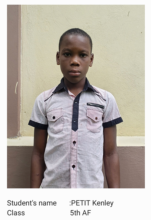 A young boy standing in front of a wall.