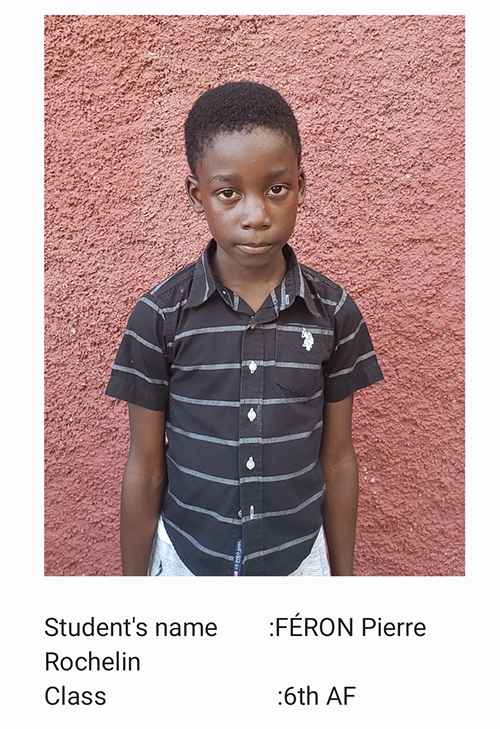 A young boy standing in front of a pink wall.