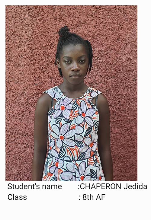 A young girl standing in front of a wall.