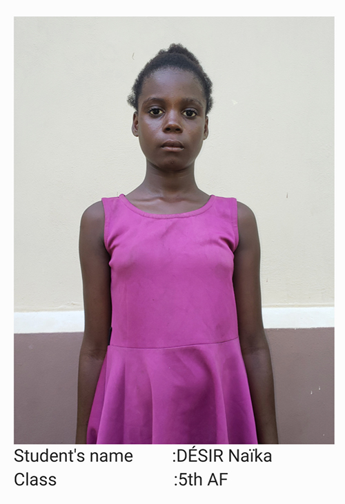 A young woman in a pink dress stands against the wall.