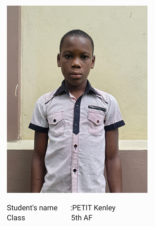 A young boy standing in front of a wall.